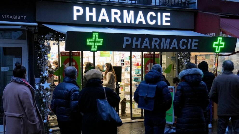 People wait in front of a pharmacy to get a COVID-19 test in Paris, France, Sunday, Jan. 9, 2022. On Friday, Dec. 9, 2022, President Emmanuel Macron announced France will make condoms free in pharmacies for anyone up to age 25 in the new year.