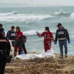 Italian Red Cross volunteers and coast guards recover a body after a migrant boat broke apart in rough seas, at a beach near Cutro, southern Italy, Feb. 26, 2023. Antonino Durso/LaPresse via AP