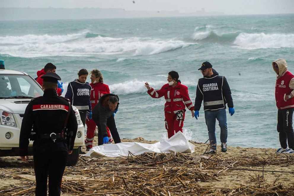Italian Red Cross volunteers and coast guards recover a body after a migrant boat broke apart in rough seas, at a beach near Cutro, southern Italy, Feb. 26, 2023. Antonino Durso/LaPresse via AP