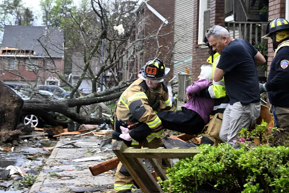 Firefighters carry a woman out of her condo after her complex was damaged by a tornado, Friday, March 31, 2023 in Little Rock, Ark. A monster storm system tore through the South and Midwest on Friday, spawning tornadoes that shredded homes and shopping centers, overturned vehicles and uprooted trees as people raced for shelter (Stephen Swofford/Arkansas Democrat-Gazette via AP)