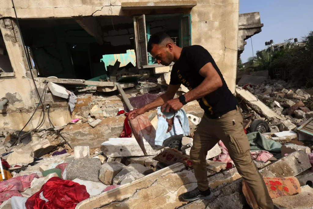 A man retrieves blood-stained clothes from the rubble of the house of Ahmed Abu Deka, the Palestinian deputy of the commander of a rocket launch unit killed by Israel. photo: SAID KHATIB / AFP
